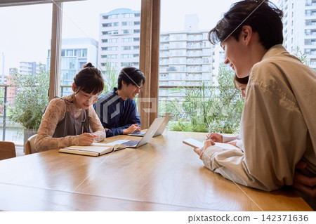 一位年輕的商務人士在咖啡館裡用筆記型電腦開會。 一位年輕的商務人士在咖啡館裡用筆記型電腦開會。 142371636
