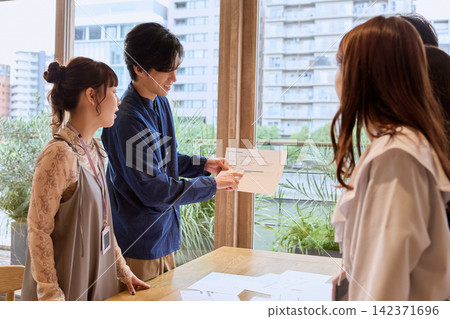 一位年輕的商人正在辦公室開會,同時展示文件。 一位年輕的商人正在辦公室開會,同時展示文件。 142371696
