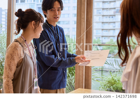 一位商人和他的同事在辦公室裡一邊展示文件一邊解釋事情。 一位商人和他的同事在辦公室裡一邊展示文件一邊解釋事情。 142371698