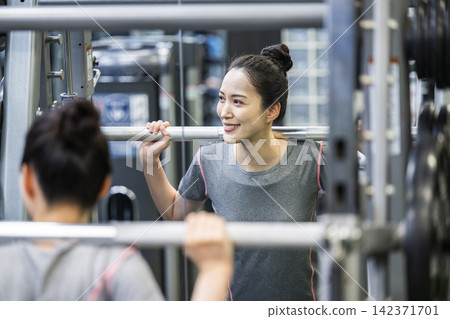 一位年輕女子正在鍛煉,她的身影映在鏡子裡。 一位年輕女子正在鍛煉,她的身影映在鏡子裡。 142371701