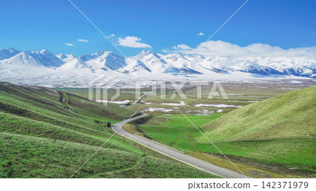 Snowy Mountain Panorama with Green Valley and Winding Road 142371979