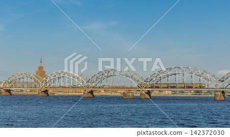 Train on Steel Arch Bridge Over River in Riga Cityscape Train on Steel Arch Bridge Over River in Riga Cityscape 142372030