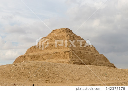 Ancient Egyptian Step Pyramid at Saqqara Under Cloudy Sky Ancient Egyptian Step Pyramid at Saqqara Under Cloudy Sky 142372176