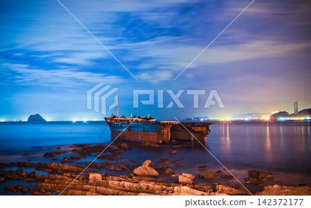 Shipwreck on Rocky Coast at Blue Hour with City Lights Shipwreck on Rocky Coast at Blue Hour with City Lights 142372177