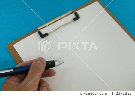 A hand holding a pen and a blank sheet of paper A hand holding a pen and a blank sheet of paper 142372282