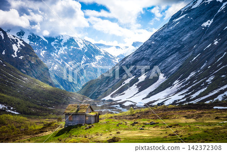 Mountain Valley Cabin with Snowy Peaks and Dramatic Sky Mountain Valley Cabin with Snowy Peaks and Dramatic Sky 142372308