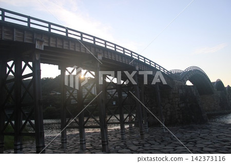 Kintaikyo Bridge, a wooden arch bridge spanning the Nishiki River in Iwakuni City, Yamaguchi Prefecture, is a beautiful Japanese landscape illuminated by the morning sun. Kintaikyo Bridge, a wooden arch bridge spanning the Nishiki River in Iwakuni City, Yamaguchi Prefecture, is a beautiful Japanese landscape illuminated by the morning sun. 142373116