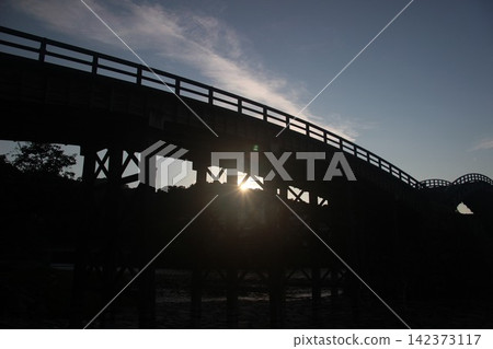 Kintaikyo Bridge, a wooden arch bridge spanning the Nishiki River in Iwakuni City, Yamaguchi Prefecture, is a beautiful Japanese landscape illuminated by the morning sun. Kintaikyo Bridge, a wooden arch bridge spanning the Nishiki River in Iwakuni City, Yamaguchi Prefecture, is a beautiful Japanese landscape illuminated by the morning sun. 142373117