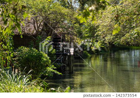 Traditional watermills line the quiet, clear stream. Traditional watermills line the quiet, clear stream. 142373554