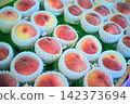 A photograph of a sales scene in the produce section, showing rows of peaches and white protective netting. 142373694