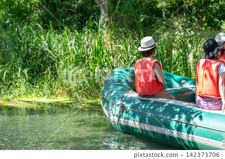 People enjoying a boating experience on a clear stream People enjoying a boating experience on a clear stream 142373706