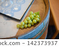 A dining space featuring green grapes and clear glasses placed on a wooden counter. 142373937