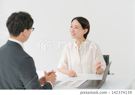 一位女士正在諮詢一位身穿西裝的男士。 一位女士正在諮詢一位身穿西裝的男士。 142374139