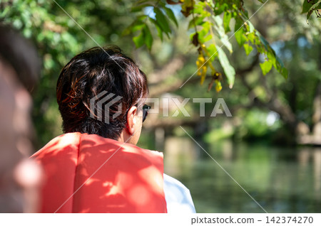 The back view of a man enjoying a boat ride while gazing at a clear stream. The back view of a man enjoying a boat ride while gazing at a clear stream. 142374270