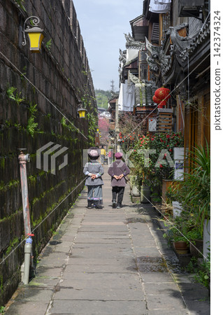 City street in the morning, with passersby, wooden houses, shops and stone wall in Fenghuang, China City street in the morning, with passersby, wooden houses, shops and stone wall in Fenghuang, China 142374324