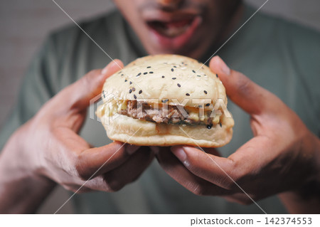 Enjoying a burger with sesame seeds in hands Enjoying a burger with sesame seeds in hands 142374553