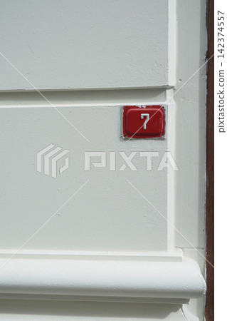 House number seven attached to a white wall 142374557