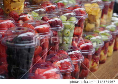 Fresh fruit cups on display at a market stand Fresh fruit cups on display at a market stand 142374567