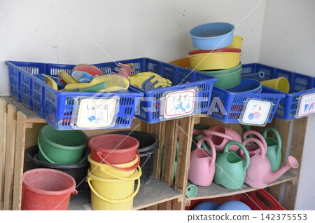 幼兒園操場上擺放著水桶和遊樂設施。 幼兒園操場上擺放著水桶和遊樂設施。 142375553