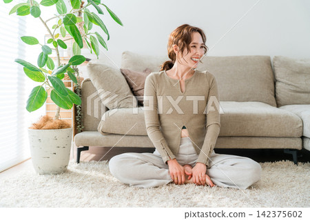 一位女士在明亮的客廳裡享受著寧靜的時光。 一位女士在明亮的客廳裡享受著寧靜的時光。 142375602