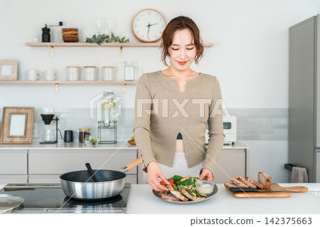 A woman preparing a healthy meal in her home kitchen. A woman preparing a healthy meal in her home kitchen. 142375663