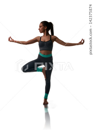 Woman in yoga tree pose wearing athletic wear on white background Woman in yoga tree pose wearing athletic wear on white background 142375874