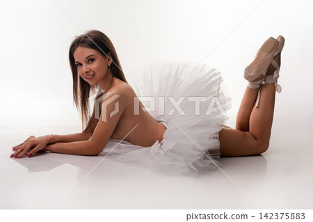 Ballerina in white tutu lying on studio floor with pointe shoes Ballerina in white tutu lying on studio floor with pointe shoes 142375883