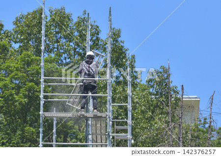 Scaffolding worker dismantling temporary scaffolding. Scaffolding worker dismantling temporary scaffolding. 142376257