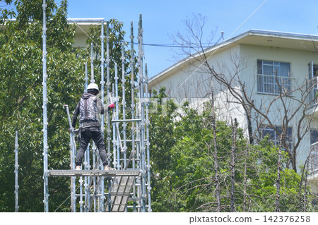 Scaffolding worker dismantling temporary scaffolding. Scaffolding worker dismantling temporary scaffolding. 142376258