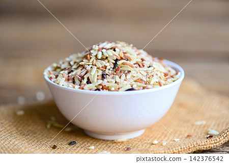 brown rice on white bowl sack  background, raw various rice color mixed thai rice for cooking food , Loonzain rice brown black red white purple health food. 142376542
