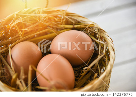 Chicken eggs in basket nest on white wooden background 142376775