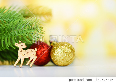 Christmas decoration pine tree with golden red balls and wooden reindeer holiday yellow bokeh background / christmas tree festive xmas winter and Happy New Year object Christmas decoration pine tree with golden red balls and wooden reindeer holiday yellow bokeh background / christmas tree festive xmas winter and Happy New Year object 142376846