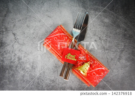 Christmas table place setting decoration with fork spoon and knife on napkin on table Christmas table place setting decoration with fork spoon and knife on napkin on table 142376918
