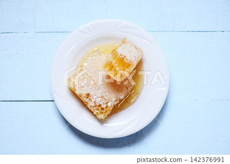 Fresh honey - Close up of yellow sweet honeycomb slice on white plate natural healthy food 142376991