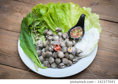 Cockle shellfish seafood plate with fresh vegetable herbs and spices on plate food Cockles background - blood cockle peeled on table with seafood sauce Cockle shellfish seafood plate with fresh vegetable herbs and spices on plate food Cockles background - blood cockle peeled on table with seafood sauce 142377041