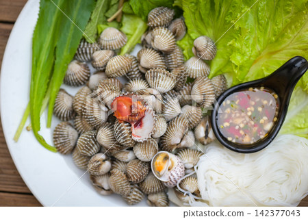 Cockle shellfish seafood plate with fresh vegetable herbs and spices on plate food Cockles background - blood cockle peeled on table with seafood sauce 142377043