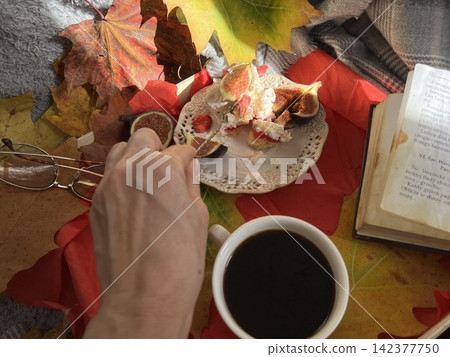 Cozy Autumn Flatlay with Female Hand Holding Fig, Coffee Cup, and Book 142377750
