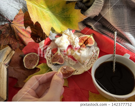 Cozy Autumn Flatlay with Female Hand Holding Fig, Coffee Cup, and Book 142377752