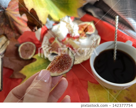 Cozy Autumn Flatlay with Female Hand Holding Fig, Coffee Cup, and Book Cozy Autumn Flatlay with Female Hand Holding Fig, Coffee Cup, and Book 142377754