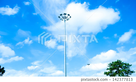 Stadium Floodlight Pole Against Blue Sky and White Clouds Stadium Floodlight Pole Against Blue Sky and White Clouds 142377813