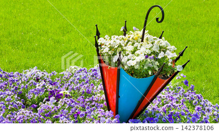 Colorful Umbrella Planter with Spring Flowers on Green Lawn 142378106