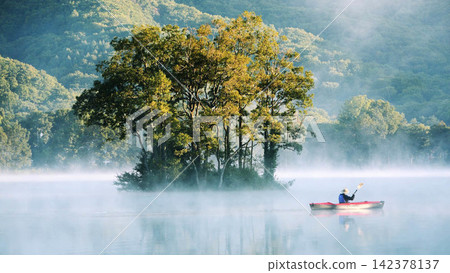 Kayaker on Misty Lake with Forest Island at Sunrise 142378137