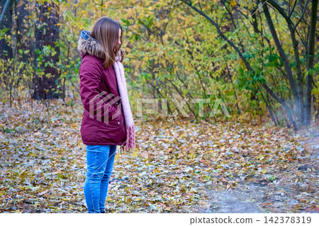 Autumn sadness.Calm woman in red jacket walking in forest park Autumn sadness.Calm woman in red jacket walking in forest park 142378319