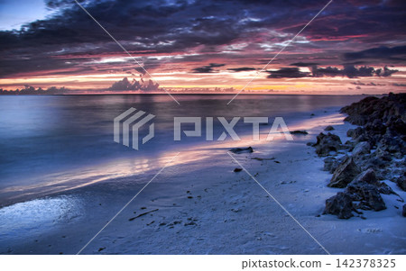 Beach Sunset Seascape with Rocky Shore and Dramatic Clouds 142378325