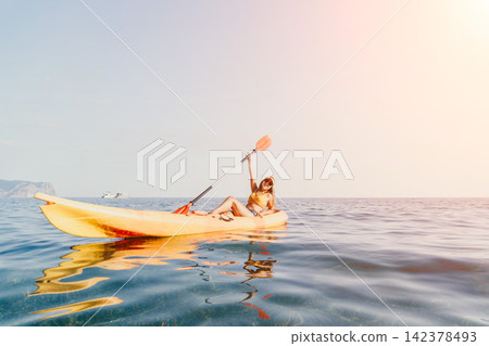Woman Kayaking Sea Paddle Summer: A woman paddles a yellow kayak in the sea on a sunny day. Woman Kayaking Sea Paddle Summer: A woman paddles a yellow kayak in the sea on a sunny day. 142378493