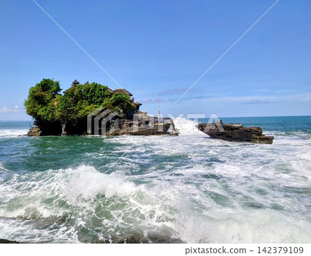 美麗的峇裡島傳統寺廟海神廟(Tanah Lot)建在海中的岩石露頭上,海浪拍打著海岸。 美麗的峇裡島傳統寺廟海神廟(Tanah Lot)建在海中的岩石露頭上,海浪拍打著海岸。 142379109