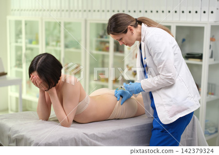 Nurse giving intramuscular injection of medication into buttock of patient who is afraid 142379324