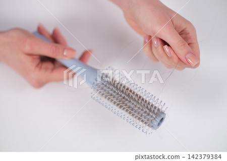 hairbrush holding loose hair in neutral indoor setting with plastic and nylon bristles, everyday use, close-up top-down perspective, gray and white tones, beauty care. hairbrush holding loose hair in neutral indoor setting with plastic and nylon bristles, everyday use, close-up top-down perspective, gray and white tones, beauty care. 142379384