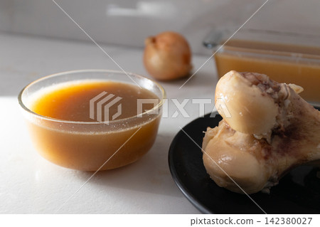 Bone Broth Preparation: Strained Stock from Chicken Leg for Nutritious Cooking Bone Broth Preparation: Strained Stock from Chicken Leg for Nutritious Cooking 142380027