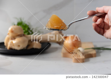 Hand holding triangular orange gel wedge on a spoon in a bright home kitchen Hand holding triangular orange gel wedge on a spoon in a bright home kitchen 142380047